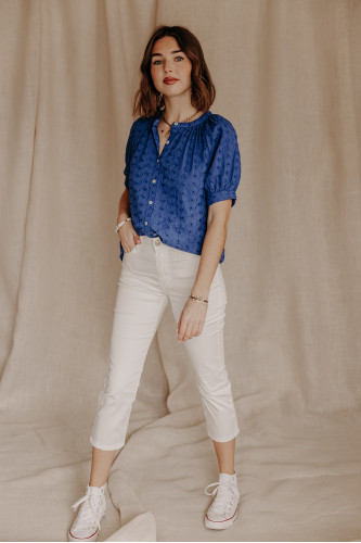 Femme avec un pantacourt blanc et une blouse bleue.