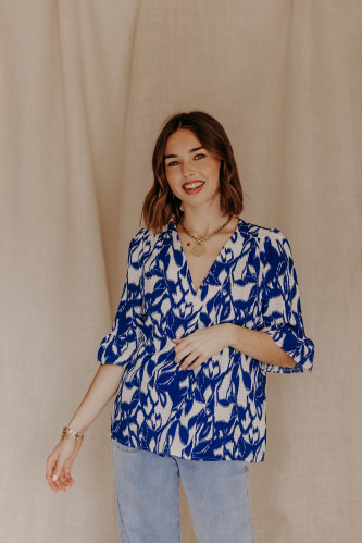 Femme portant une blouse imprimée bleue et blanche.