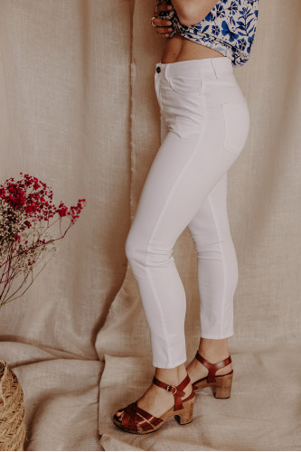 Femme de profil avec un pantalon blanc.