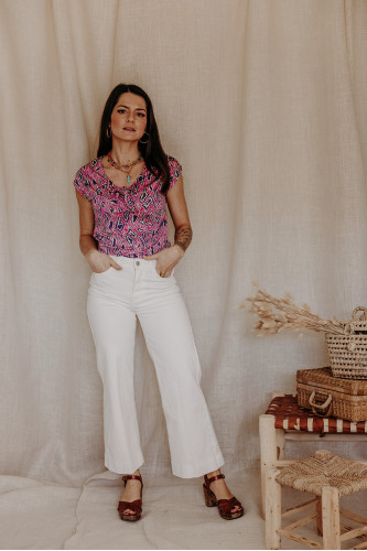 Femme qui porte un top imprimé et un jean blanc.