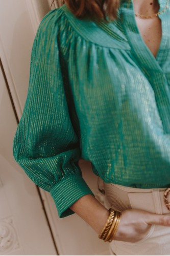 Détails d'une blouse en gaze de coton verte portée par une femme debout