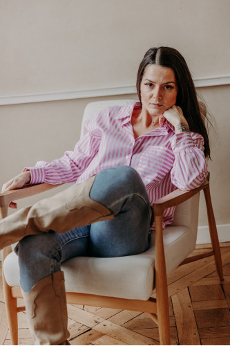 Femme assise avec un jean et une chemise.