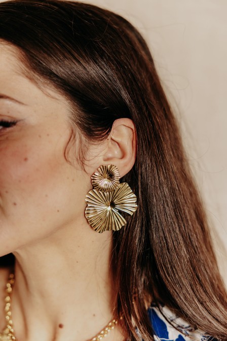 Femme qui porte des boucles d'oreilles dorées. Femme qui porte des boucles d'oreilles dorées.