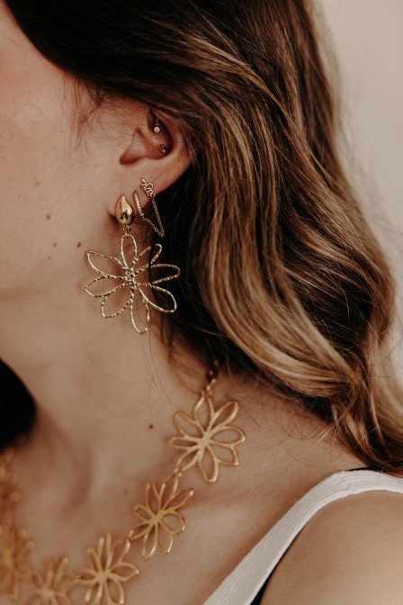 femme qui porte des boucles d'oreilles fleurs dorées femme qui porte des boucles d'oreilles fleurs dorées