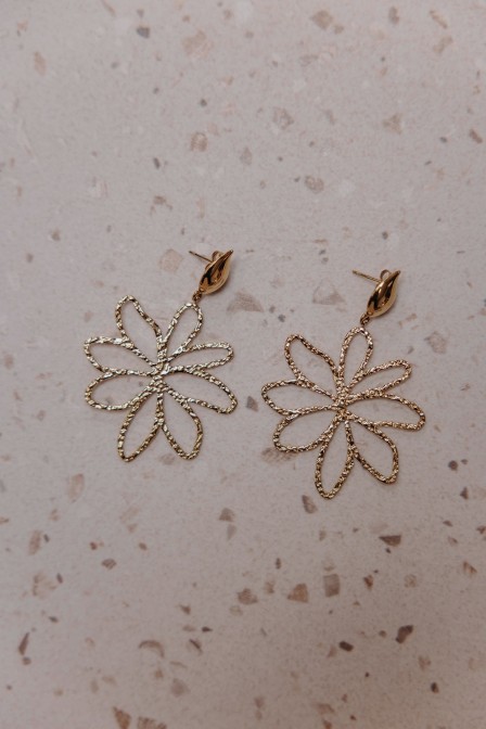 femme qui porte des boucles d'oreilles fleurs dorées femme qui porte des boucles d'oreilles fleurs dorées