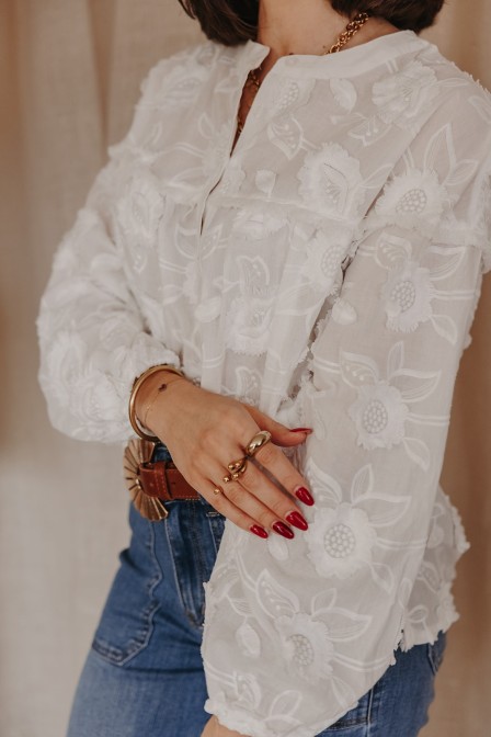 Femme avec une blouse blanche aux détails brodés.