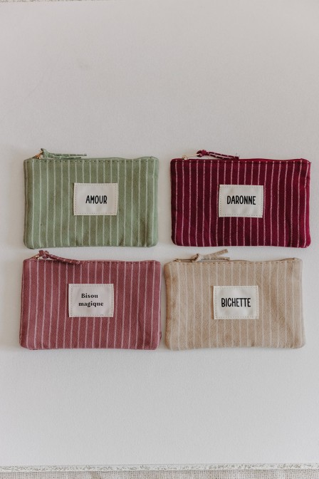 Pochette bordeaux posée sur des fleurs.