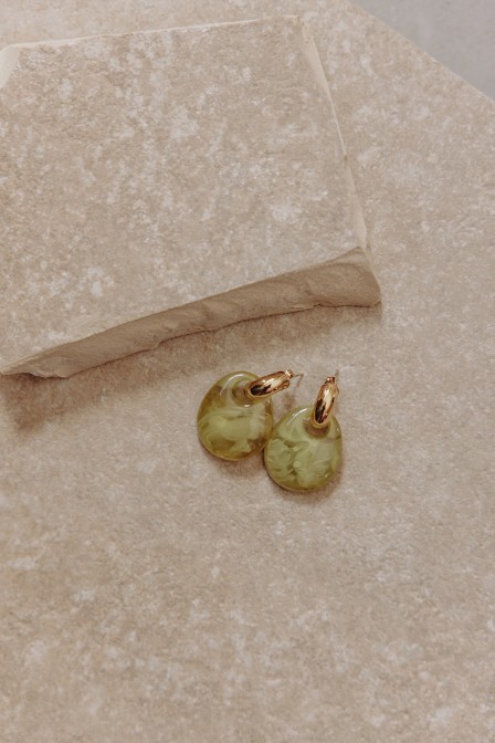 Boucles d'oreilles dorées et olive posées sur une pierre. Boucles d'oreilles dorées et olive posées sur une pierre.