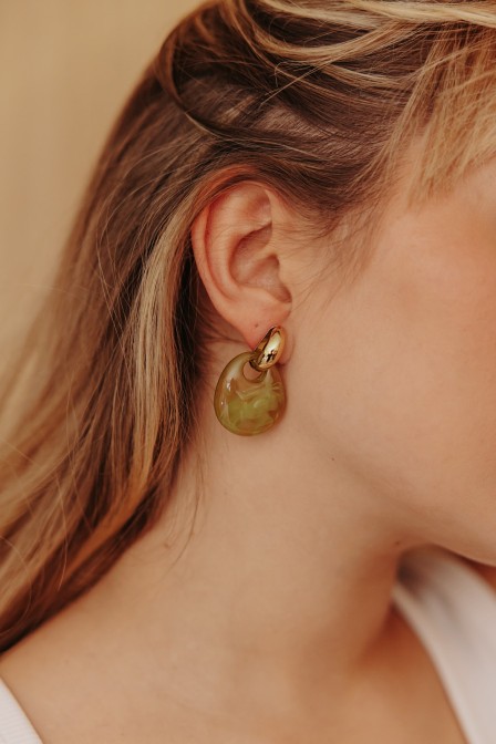 Boucles d'oreilles dorées et olive posées sur une pierre. Boucles d'oreilles dorées et olive posées sur une pierre.